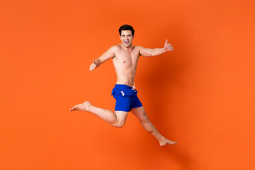 Fototapeta na wymiar Ecstatic smiling shirtless handsome man jumping with hands thumb up