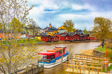 Scenic view of the Finnish city of Parvoo. River pleasure boat. Neat outbuildings. Spring nature. Multicolored buildings along the city promenade.