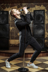 Young artistic man singing with microphone