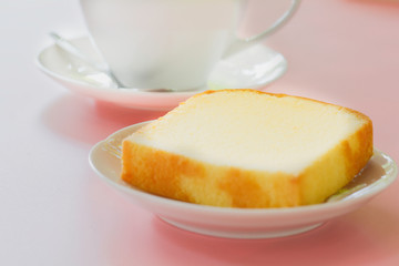 Piece of butter cake on white dish served with cup of black coffee. Times to relax concept.