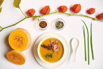 Luxury dinner from cream soup with meat and tea with mint prepared for guest in oriental restaurant. Creative still life on white tablecloth from above. Pumpkin and physalis lying near meal.