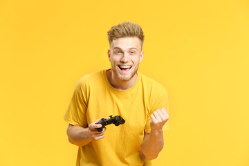 Portrait of happy young man playing video games on color background