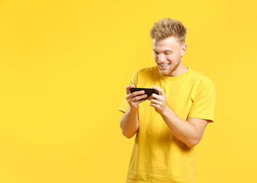 Portrait of happy young man with mobile phone on color background