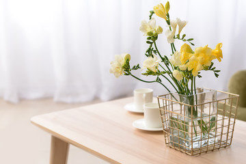 Vase with beautiful freesia flowers on table in room