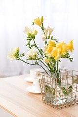 Vase with beautiful freesia flowers on table in room