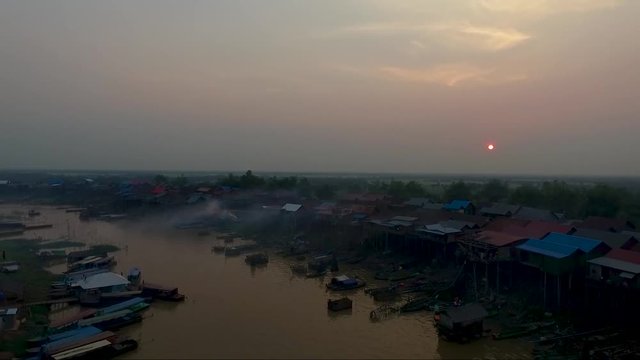 view of sunset in the background and  pull back over the river, pan down on fishermen nets. Tonle sap, mekong river. Pile of boats parked on the river.
