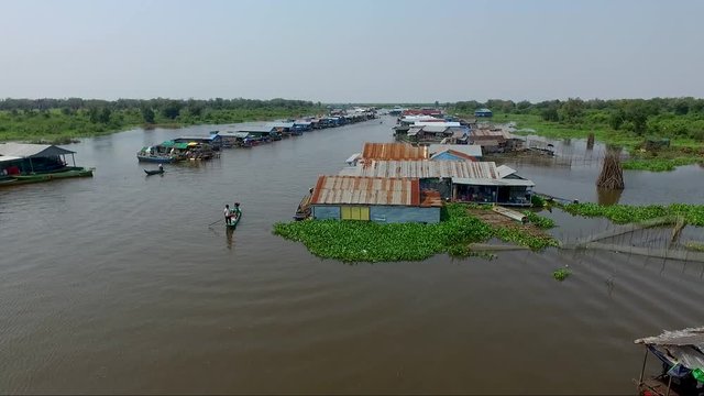 View of a fishermen paddling and pushing a boat in the mekong river ,  a view of fishermen village int he background