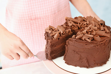 Woman with tasty chocolate cake at table, closeup