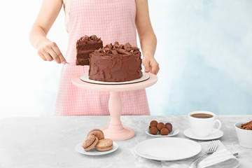 Woman with tasty chocolate cake at table
