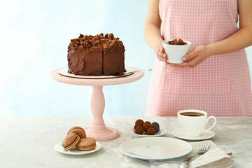 Woman with tasty chocolate cake at table