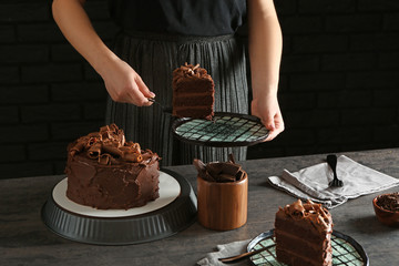 Woman with tasty chocolate cake at table