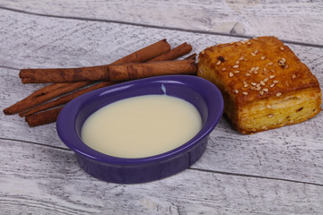 Condenced milk in the bowl with sinnamon and pastry