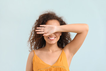 Young African-American woman covering her eyes on light background
