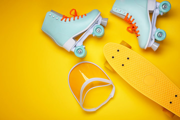 Vintage roller skates, visor and skateboard on color background