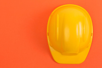 Yellow construction helmet on an orange background, protection and safety concept