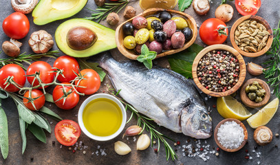 Raw dorado fish with spices and vegetables on the graphite board.