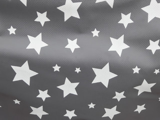 Different sized decorative white stars detail pattern on plastic foil background.