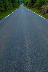 View of a long, wet road with white stripes on the sides.