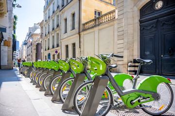 Popular hybrid bicycles with electric motors stand in row on street of Paris ready to ride everyone...
