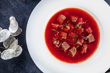 Top view Borscht, ukrainian cuisine sour soup, with meat, potato, beetroots. food background. Red soup in bowl with copy space for design. photo for menu