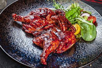 Close up on Chicken tabaka, grilled chicken. Traditional Georgian cuisine. pan-fried chicken served on dark plate. Food photo background for menu. Cope space.