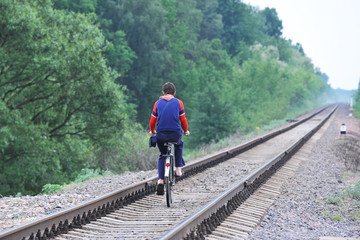 Fototapeta na wymiar boy on a bike. breaking all the rules. going along the railway