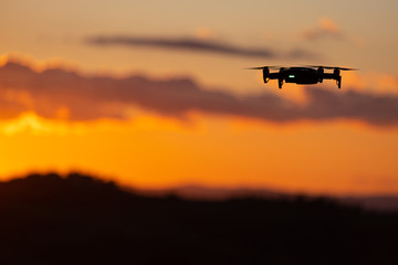 Fototapeta na wymiar Flying silhouette of drone against sunset. Flying silhouette of drone against beautiful sunset sky