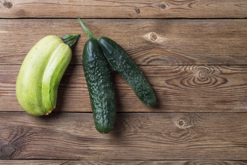 Trendy ugly organic natural squash and cucumber on natural wooden table. Copy space.