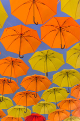 Obraz premium Yellow and orange umbrellas hanging in the air.