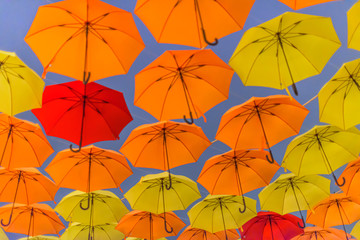 Yellow and orange umbrellas hanging in the air.