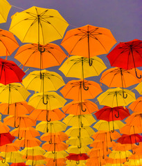 Fototapeta na wymiar Yellow and orange umbrellas hanging in the air.