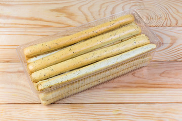 Breadsticks with Italian herbs in container on a rustic table