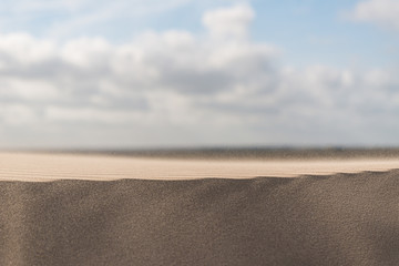 Wind blowing over a sand dune in a desert.