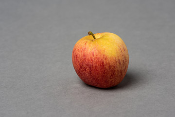Red and yellow apple on grey background.