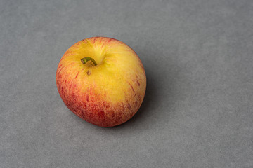 Red and yellow apple on grey background.