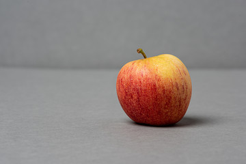 Red and yellow apple on grey background.