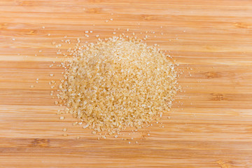 Handful of the brown sugar on a wooden surface