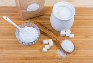 White sugar in different forms on a wooden surface