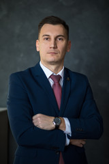 Portrait of young intelligent man lawyer standing with crossed arms in modern office building...