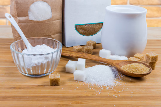 White and brown sugar in different forms on wooden surface