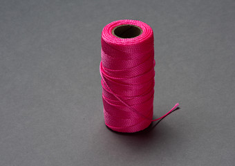A roll of pink string on grey background.