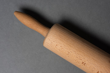 Woden rolling pin on grey background.