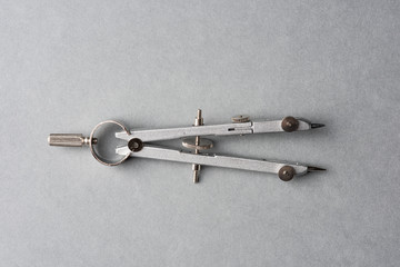 A metal compass on grey background