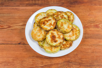 Vegetable marrows fried in batter on dish on rustic table