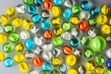 Yellow, green, blue and red glass marbles on a table.