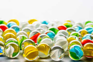Yellow, green, blue and red glass marbles on a table.