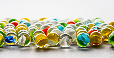 Yellow, green, blue and red glass marbles on a table.