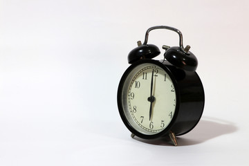 Twin bell alarm clock black color on six o'clock put on the white floor.