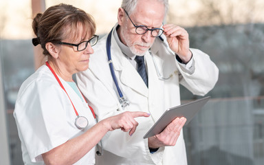 Two doctors discussing about medical report on tablet
