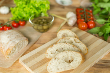 Sliced bread, ciabatta on wooden background. Preparation for the preparation of bruschetta.